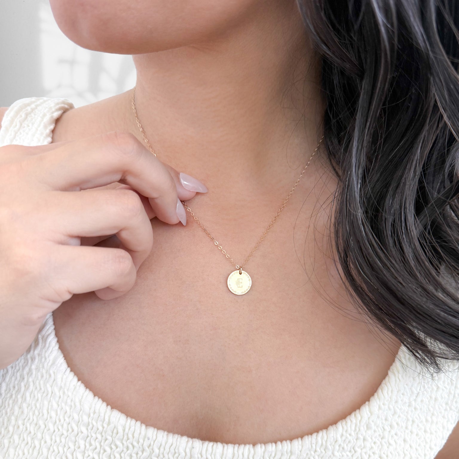 Woman wearing the Flora Monogram Necklace with a floral-initial charm resting just below the collarbone.