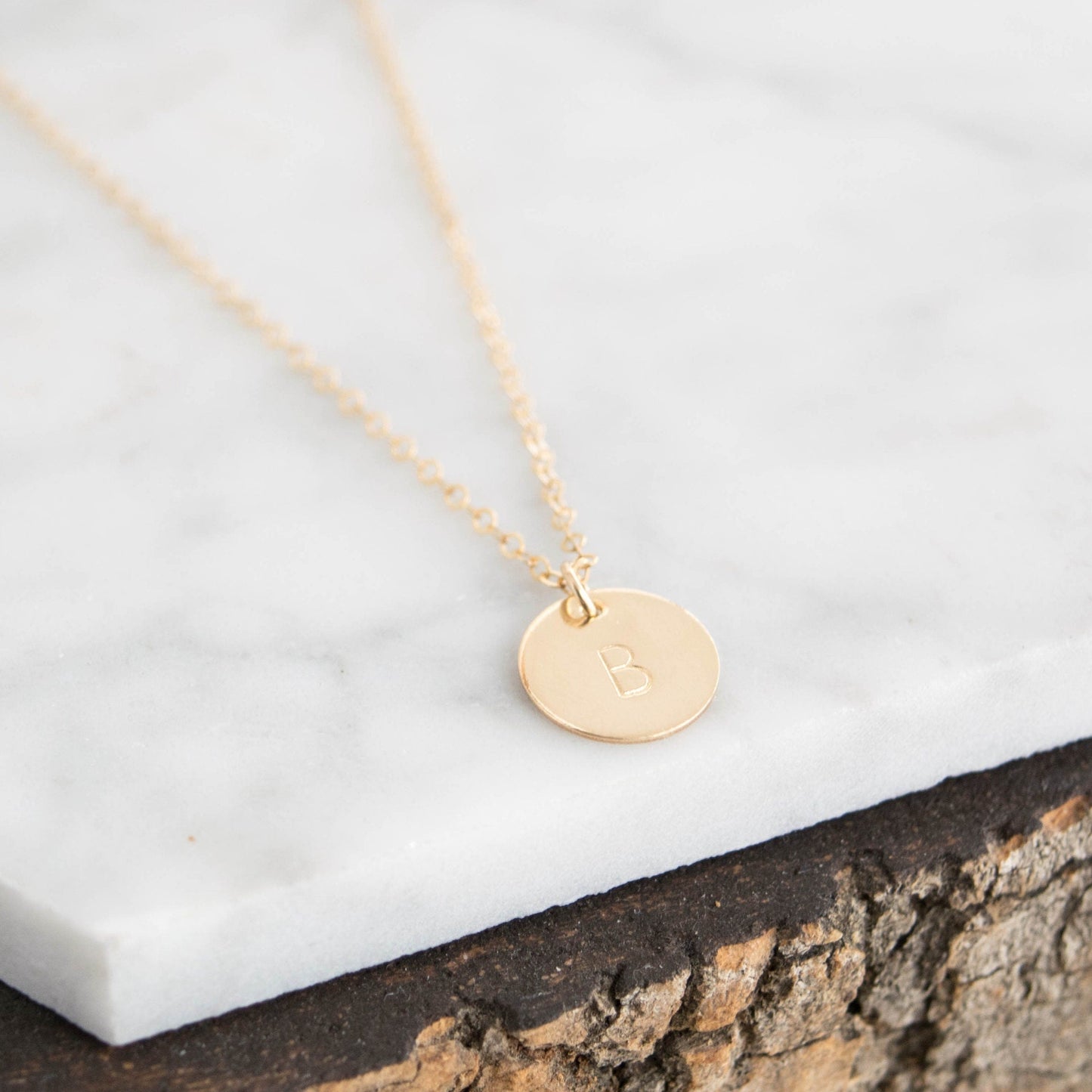 Customize your look with the Aster 1/2" Disc Monogrammed Initial Necklace, a minimalist 14K gold-filled or sterling silver disc necklace delicately hand-stamped with an initial of your choice.