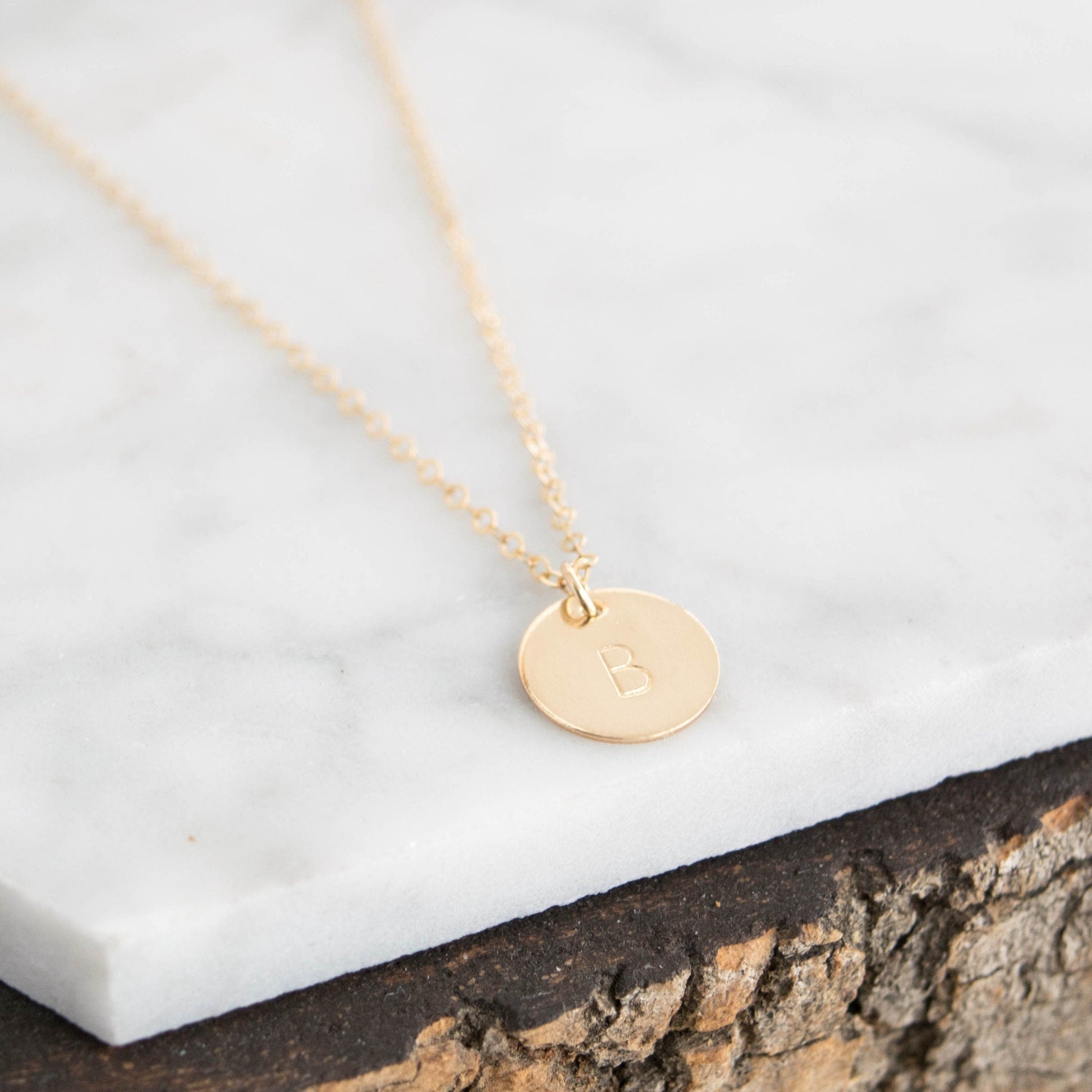 Customize your look with the Aster 1/2" Disc Monogrammed Initial Necklace, a minimalist 14K gold-filled or sterling silver disc necklace delicately hand-stamped with an initial of your choice.