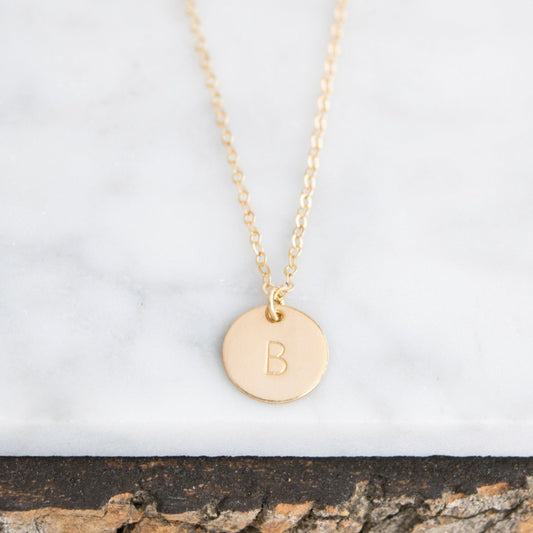 Customize your look with the Aster 1/2" Disc Monogrammed Initial Necklace, a minimalist 14K gold-filled or sterling silver disc necklace delicately hand-stamped with an initial of your choice.