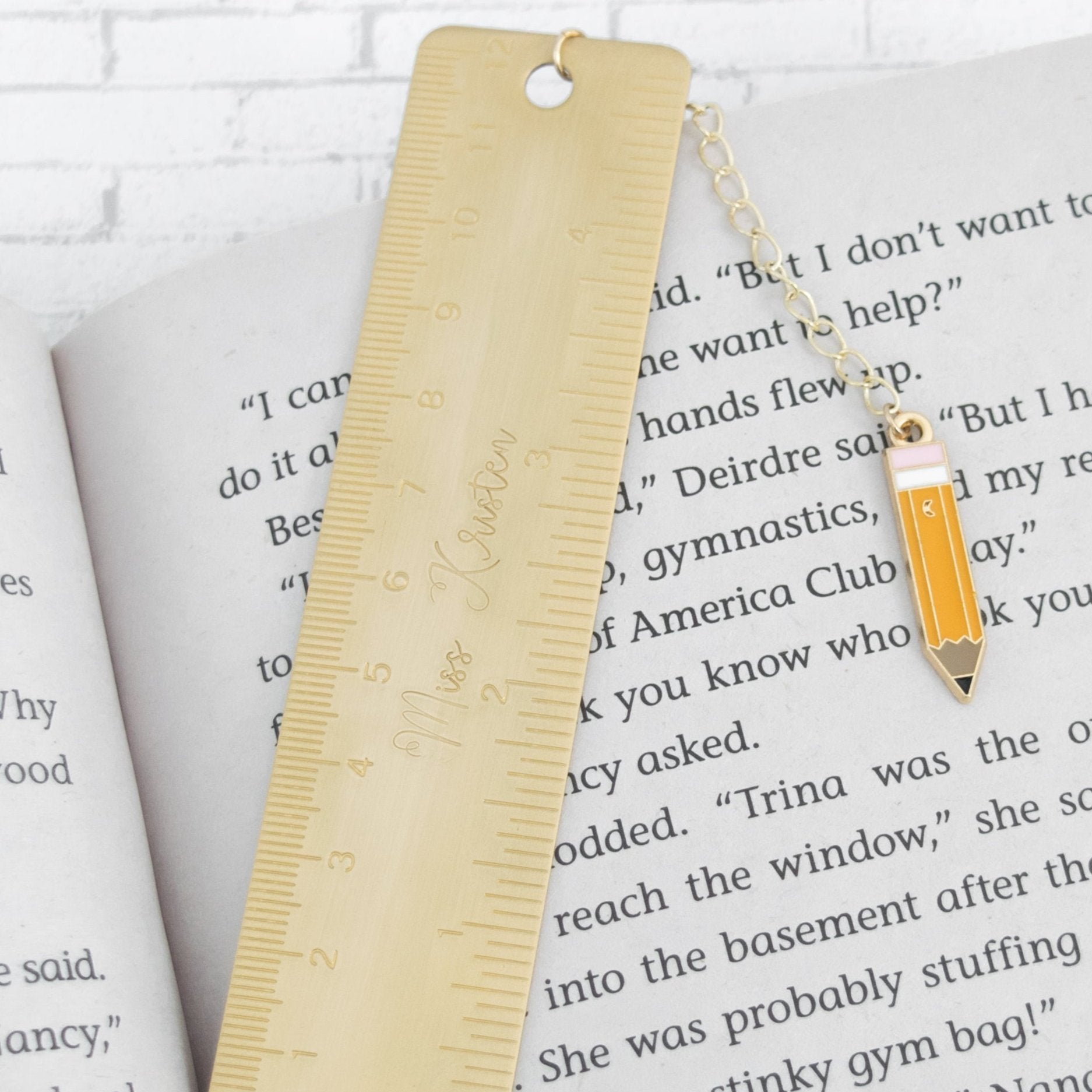 Personalized Teacher Brass Bookmark with pencil charm on a book