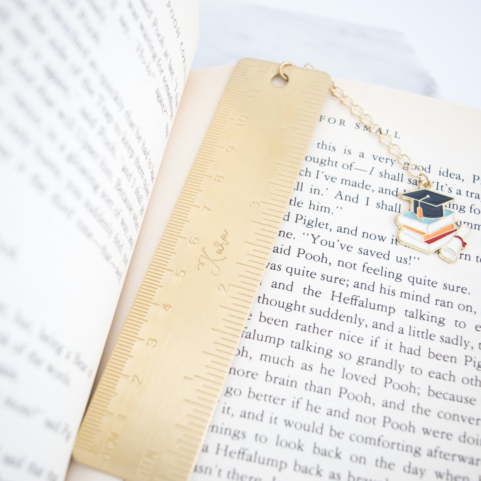 Personalized brass graduation bookmark with hand-stamped name and graduation cap charm.