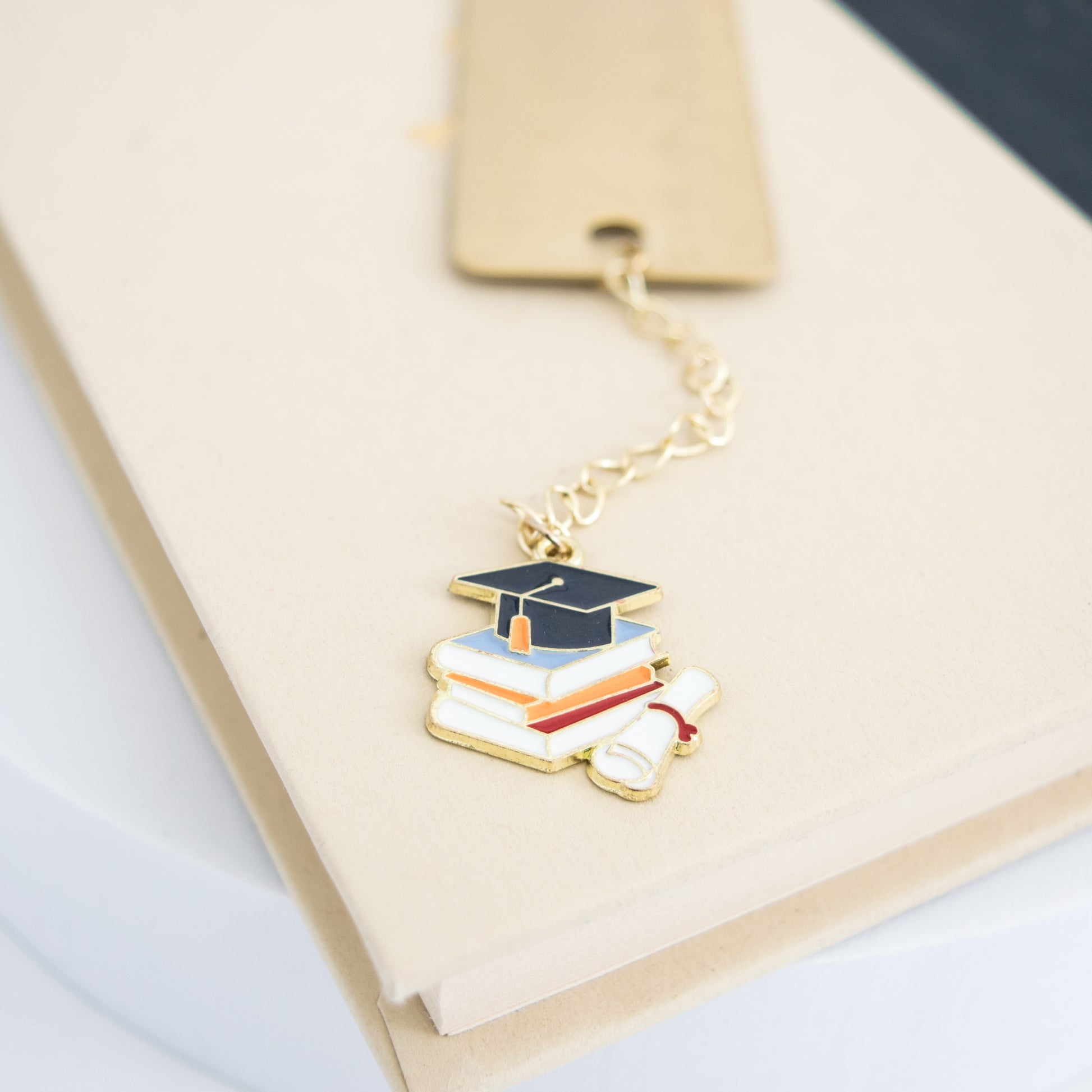Personalized brass graduation bookmark with hand-stamped name and graduation cap charm.