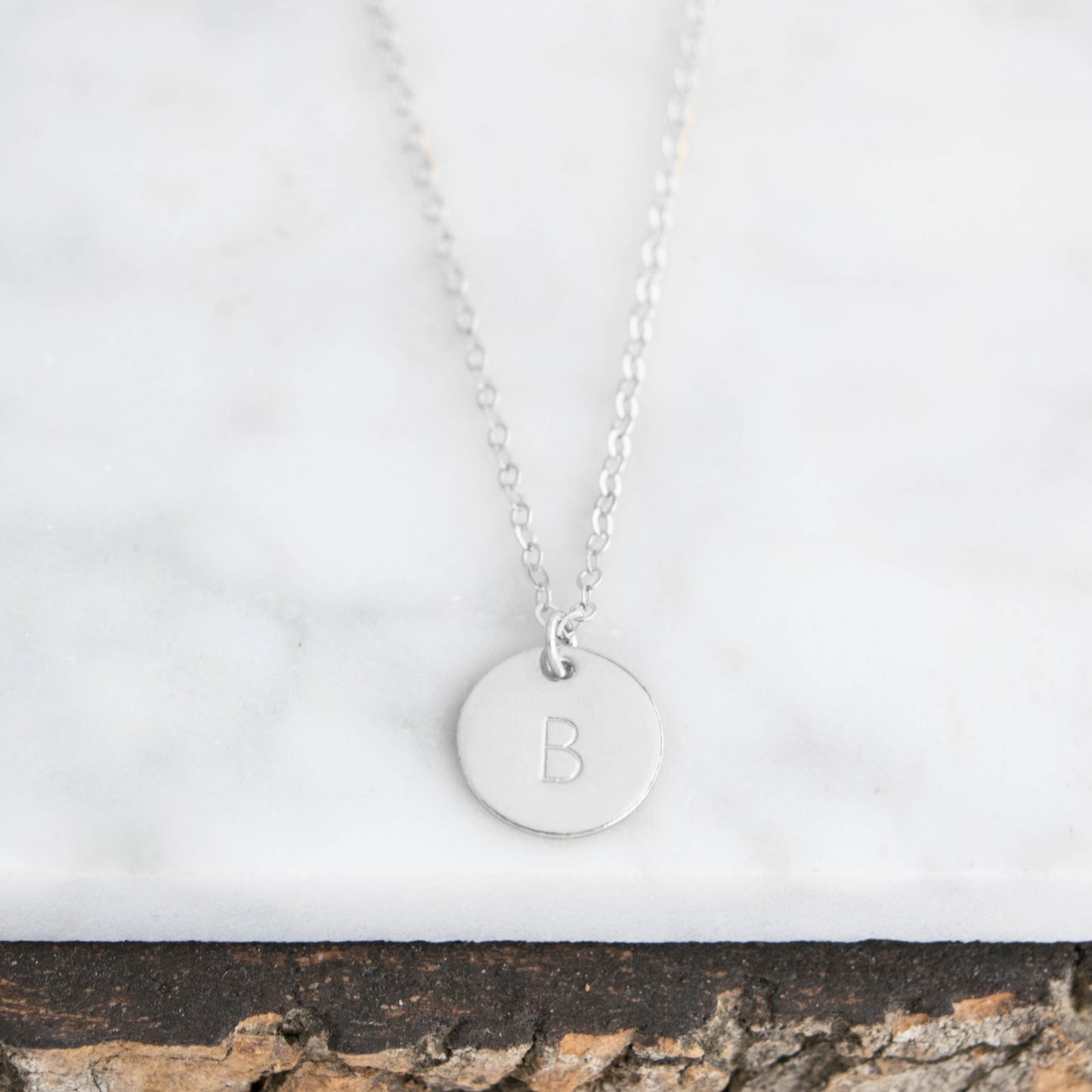 Customize your look with the Aster 1/2" Disc Monogrammed Initial Necklace, a minimalist 14K gold-filled or sterling silver disc necklace delicately hand-stamped with an initial of your choice.