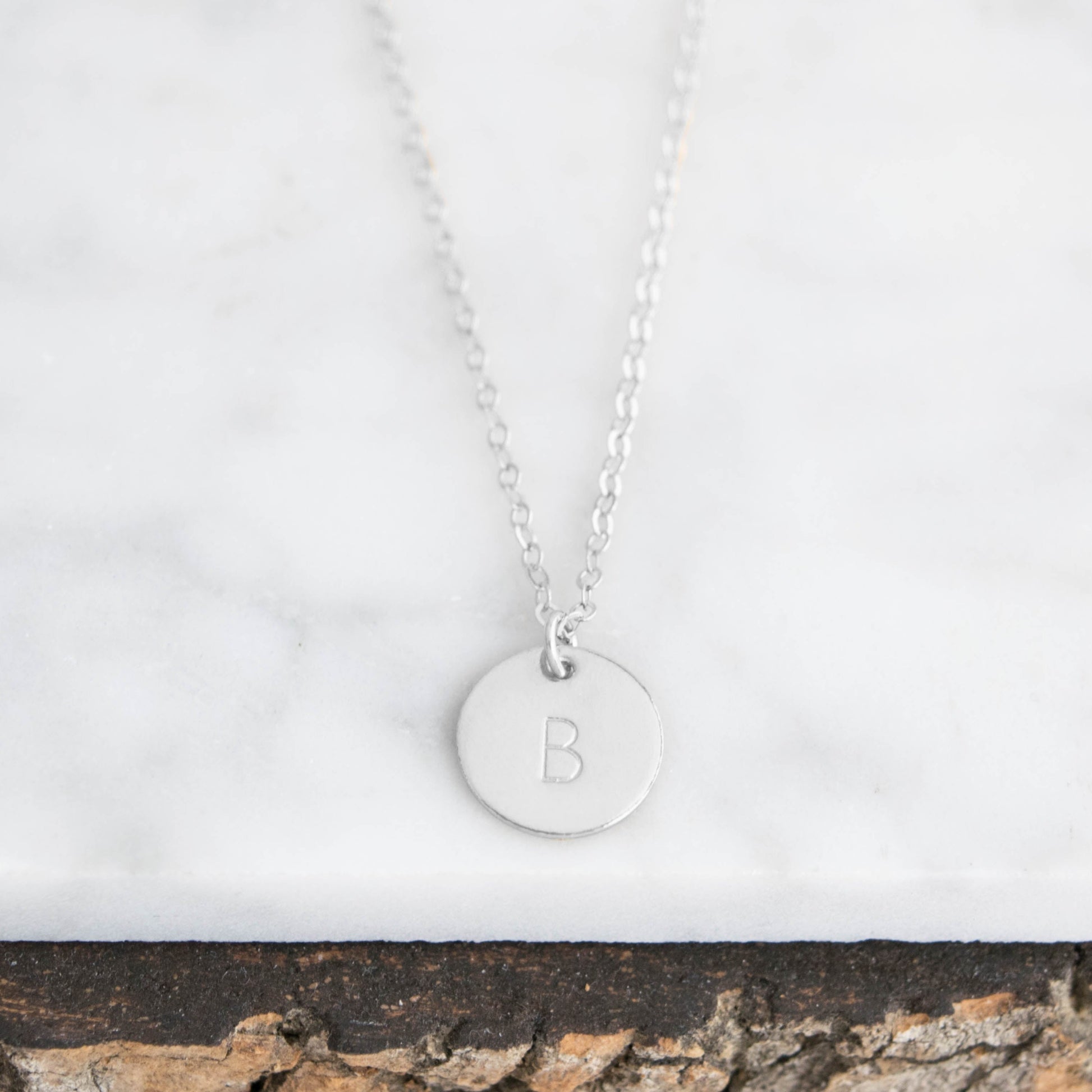 Customize your look with the Aster 1/2" Disc Monogrammed Initial Necklace, a minimalist 14K gold-filled or sterling silver disc necklace delicately hand-stamped with an initial of your choice.