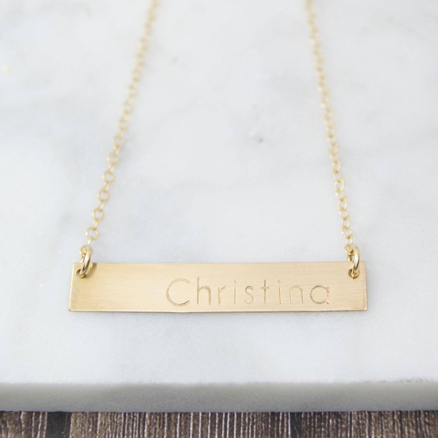 Create a truly unique piece with the Belina Bar Necklace, delicately hand-stamped with a name or message of your choice, featuring a rectangular bar pendant suspended from a dainty cable chain.