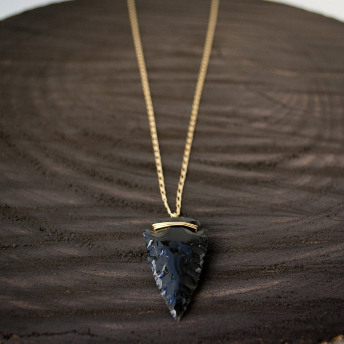 A hand-knapped obsidian arrowhead suspended on a curb figaro chain crafted in your choice of 14k gold-filled or sterling silver, hand-wrapped with corresponding wire, exuding clean elegance.