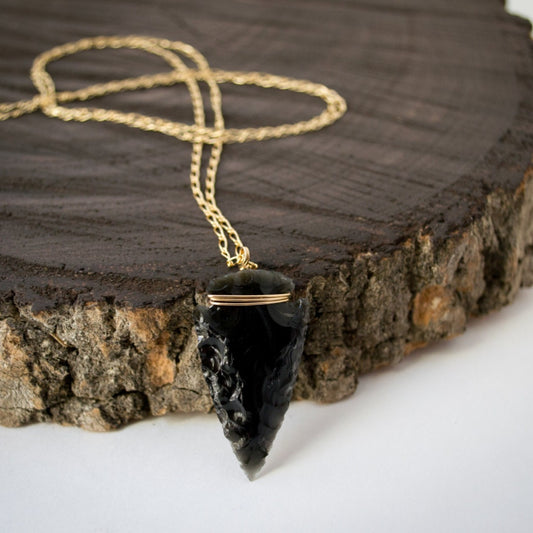 A hand-knapped obsidian arrowhead suspended on a curb figaro chain crafted in your choice of 14k gold-filled or sterling silver, hand-wrapped with corresponding wire, exuding clean elegance.