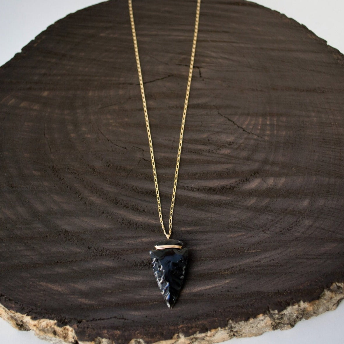 A hand-knapped obsidian arrowhead suspended on a curb figaro chain crafted in your choice of 14k gold-filled or sterling silver, hand-wrapped with corresponding wire, exuding clean elegance.